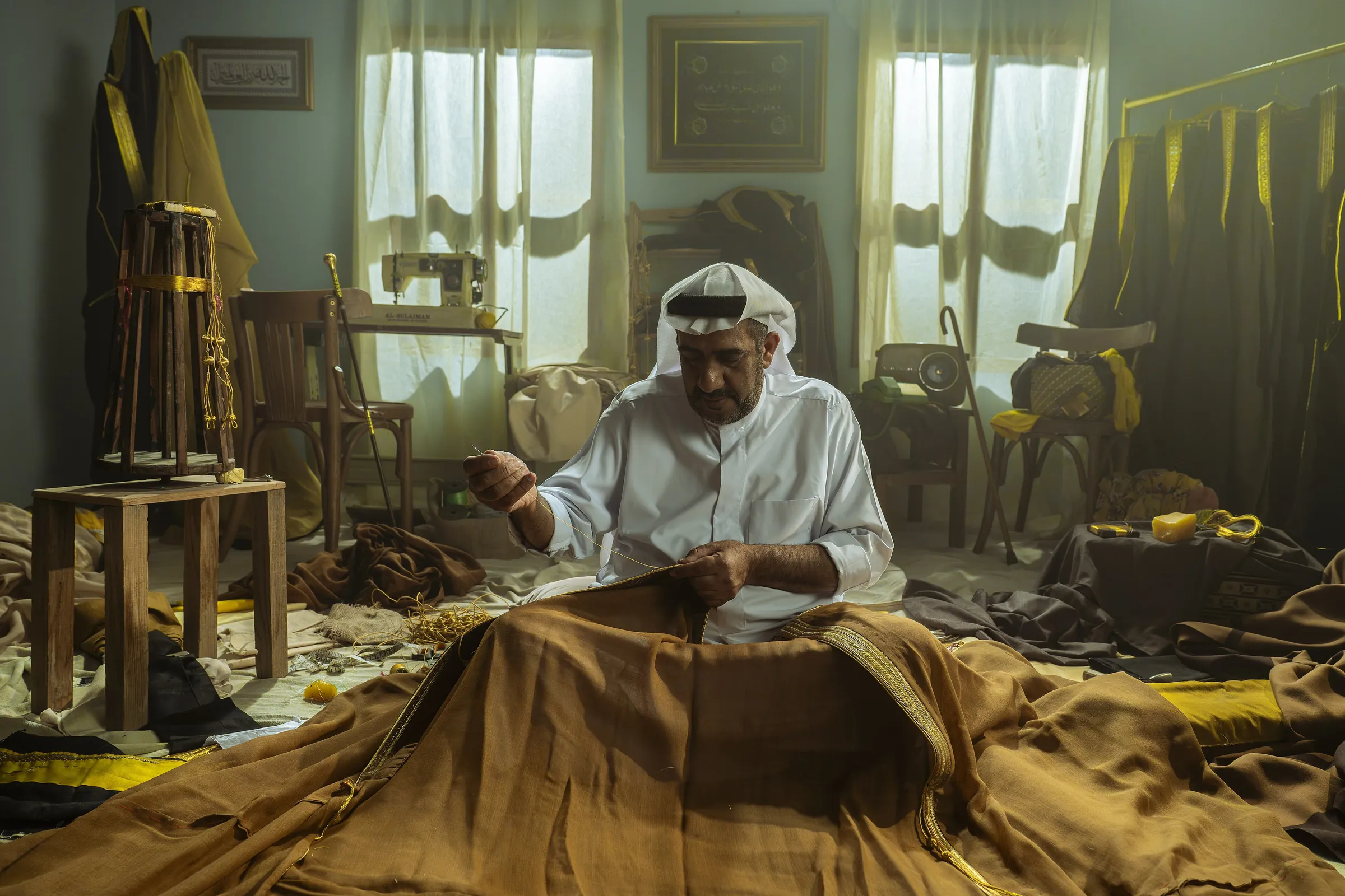 حرفي من الأحساء يخيط البشت الحساوي يدويًا في ورشته